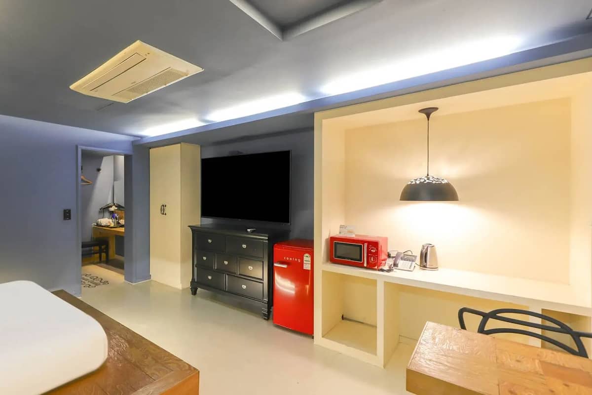 A compact living space with a kitchenette, a flat-screen TV, and a dining area.