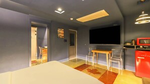 A room with a bed, a desk, two chairs, a TV, and a red appliance. - 747 Motel (Gimcheon)