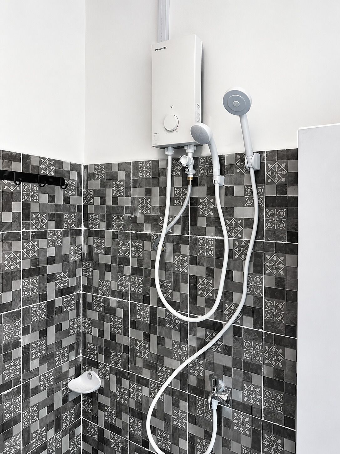 A bathroom with a shower, a toilet, and a wall-mounted heater.