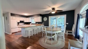 Una cocina amplia con armarios blancos, una isla central y un comedor con sillas.