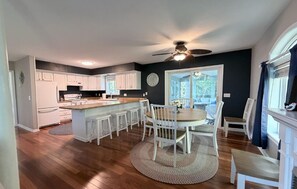 Une cuisine spacieuse avec des meubles blancs, un îlot central et un coin repas équipé de chaises.