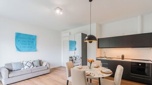 A modern living room with a sofa, dining table, and kitchen area.
