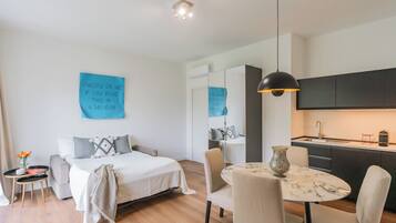 Una habitación de hotel moderna con cama, mesita de noche, silla y una pequeña mesa de comedor con sillas.