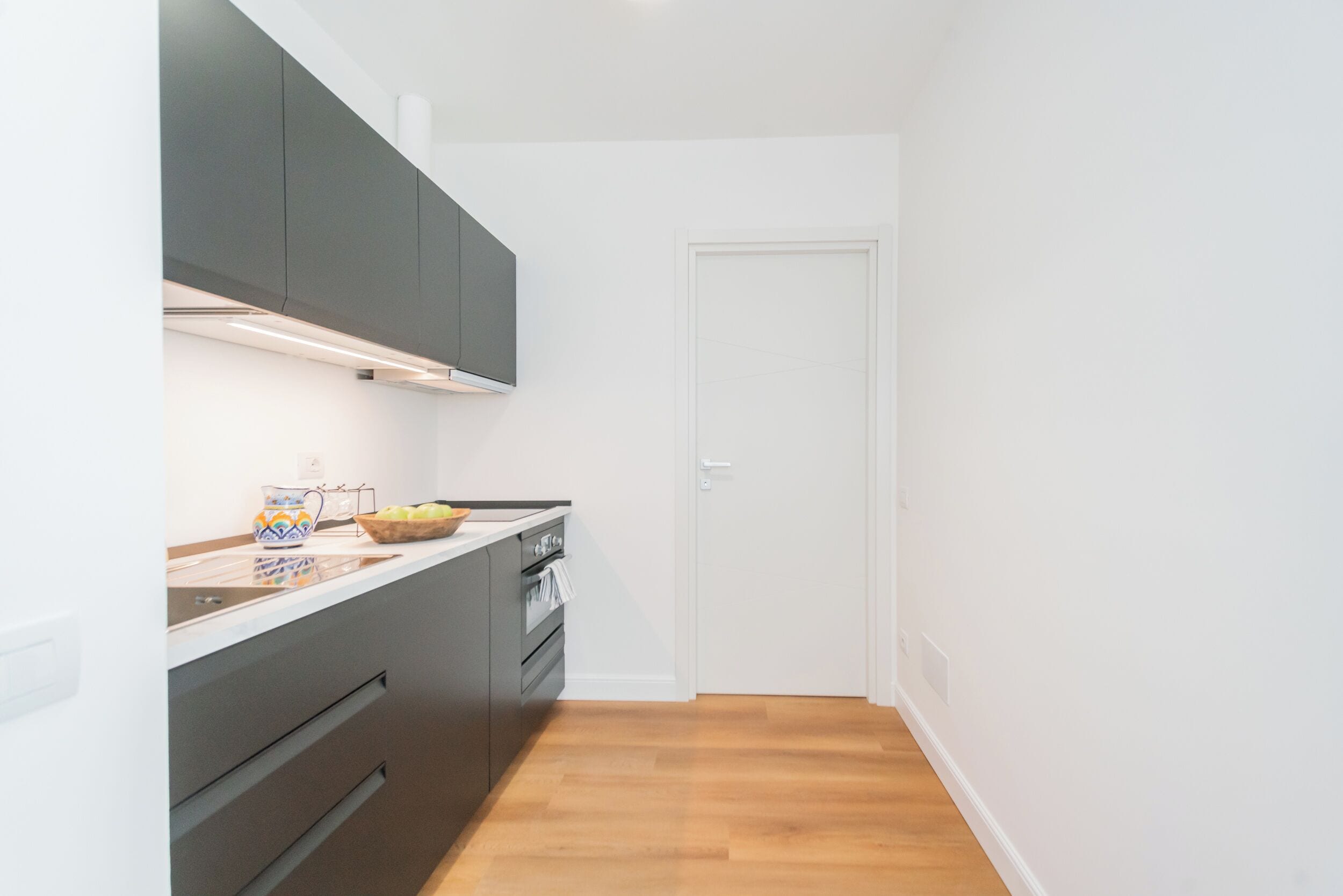 Une cuisine moderne avec des meubles de couleur sombre, un plan de travail et une porte.