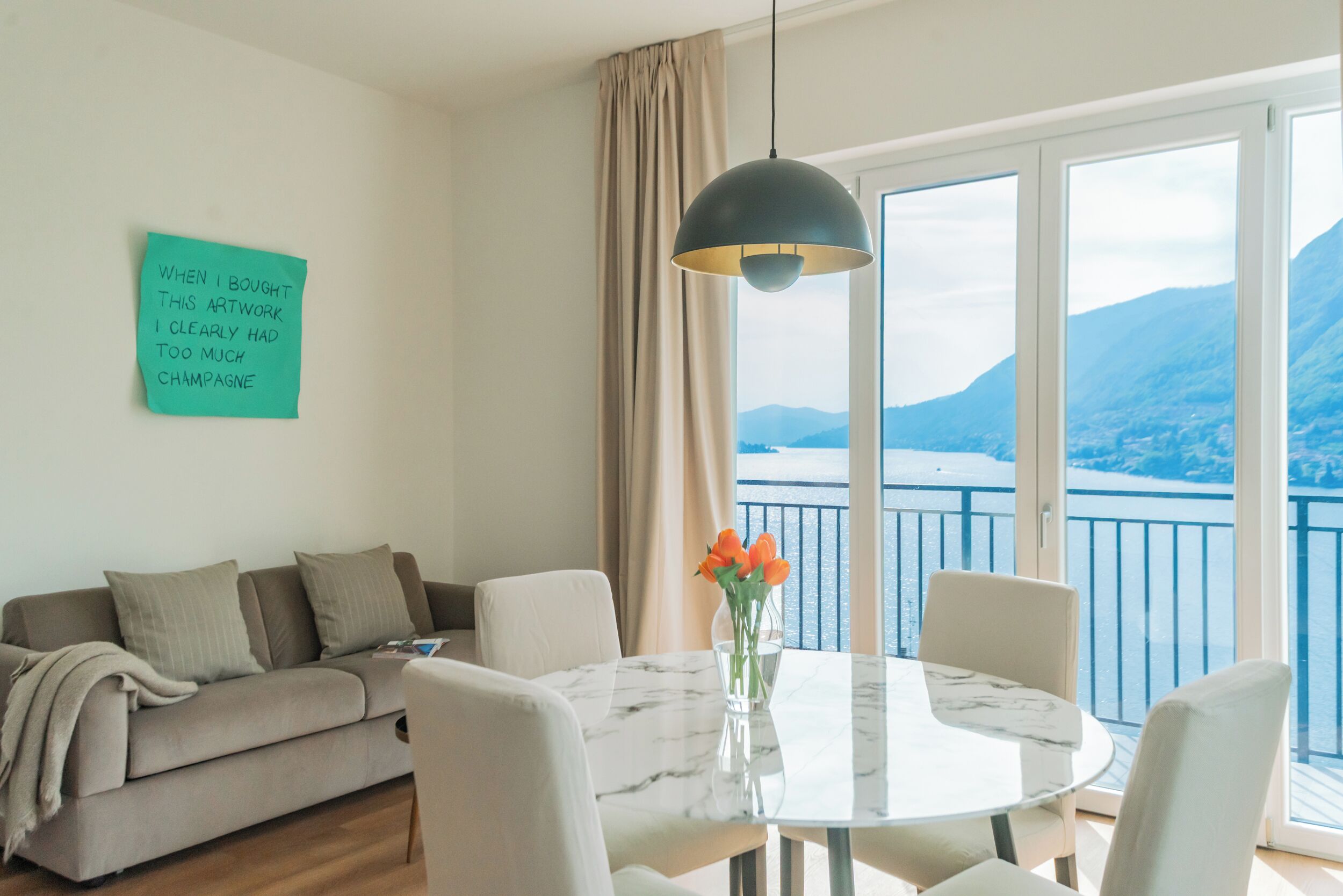 Un salon moderne avec un canapé, une table ronde et une vue sur la mer grâce à de grandes fenêtres.