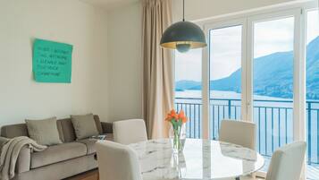 Un salon moderne avec un canapé, une table ronde et une vue sur la mer grâce à de grandes fenêtres.