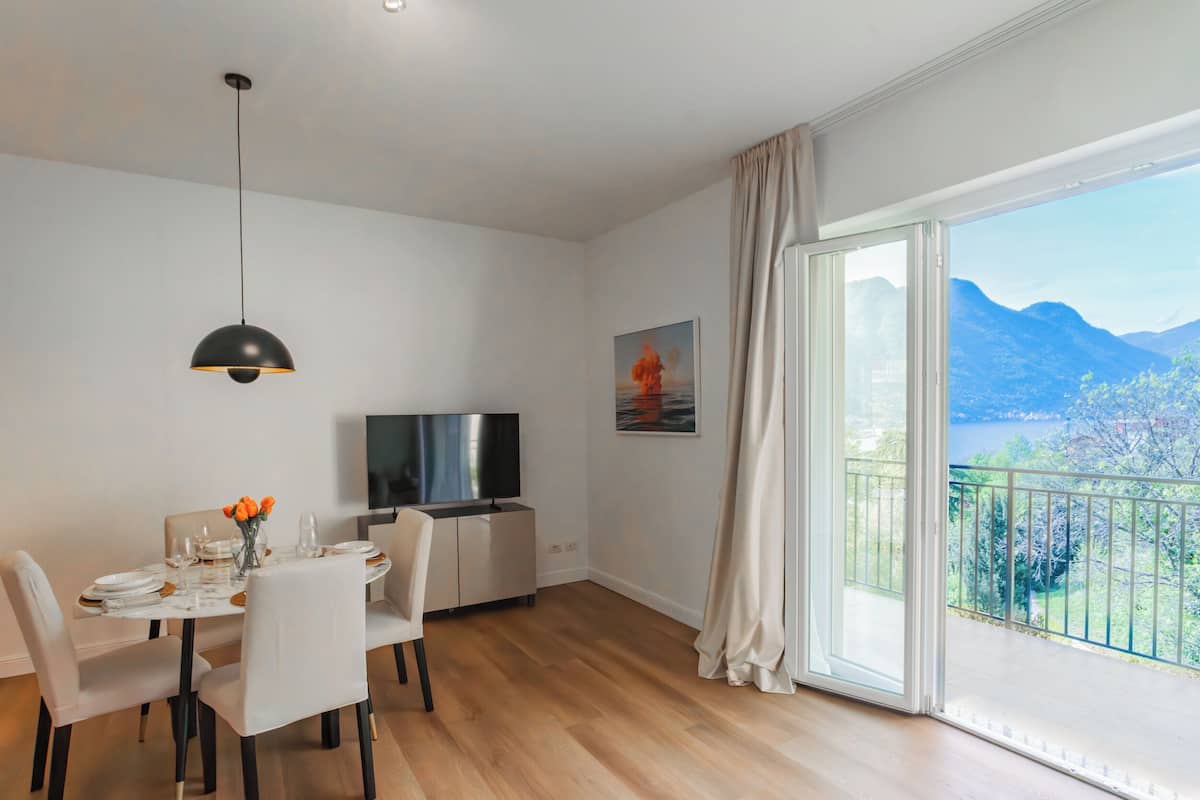 A dining area with a table set for four, a TV, and a painting on the wall.