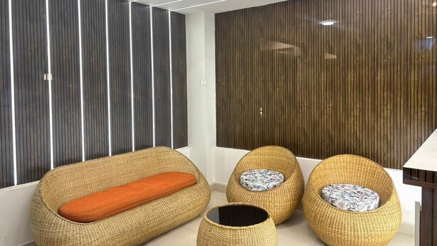 A modern living room with a sofa, two round poufs, and a small table. - The Happy Nest- A Boutique stay only 5 mins from Assam State Zoo (Guwahati)