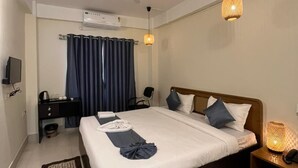 A modern hotel room with a bed, a desk, a chair, a TV, and a ceiling fan. - The Happy Nest- A Boutique stay only 5 mins from Assam State Zoo (Guwahati)
