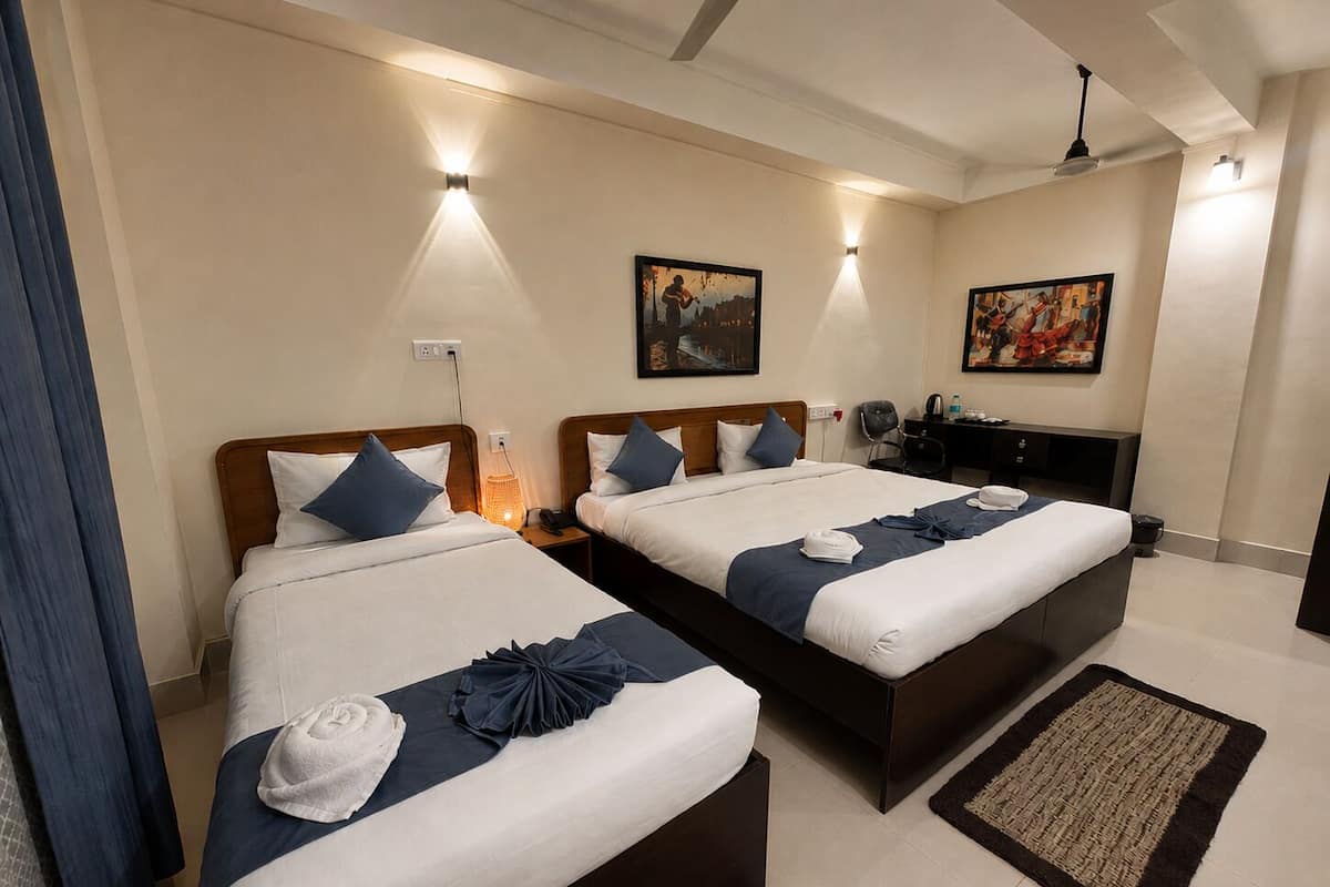A hotel room with two beds, a desk, and a chair.
