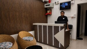 A reception area with a modern design, including a reception desk, wicker chairs, and a television mounted on the wall. - The Happy Nest- A Boutique stay only 5 mins from Assam State Zoo (Guwahati)