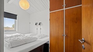 Una camera da letto con un letto, una finestra, un armadio in legno e due lampade a parete.