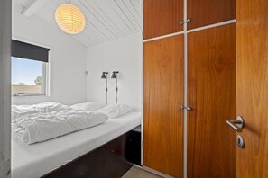 Ein Schlafzimmer mit einem Bett, einem Fenster, einem Holzschrank und zwei Wandleuchten.