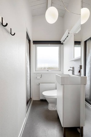 Ein modernes Badezimmer mit Toilette, Waschbecken und Fenster.