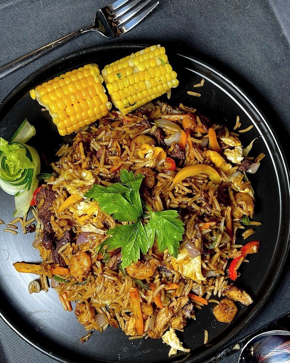 Un plato de arroz frito con verduras y elote.