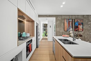 Eine moderne Küche mit weißen Schränken, einer zentralen Kochinsel mit Spüle und Blick auf einen Balkon.