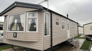 Casa móvil con un porche pequeño, una antena parabólica y una rampa para facilitar el acceso.