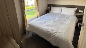 Habitación de hotel con cama, mesita de noche, ventana con cortinas y vista al exterior.