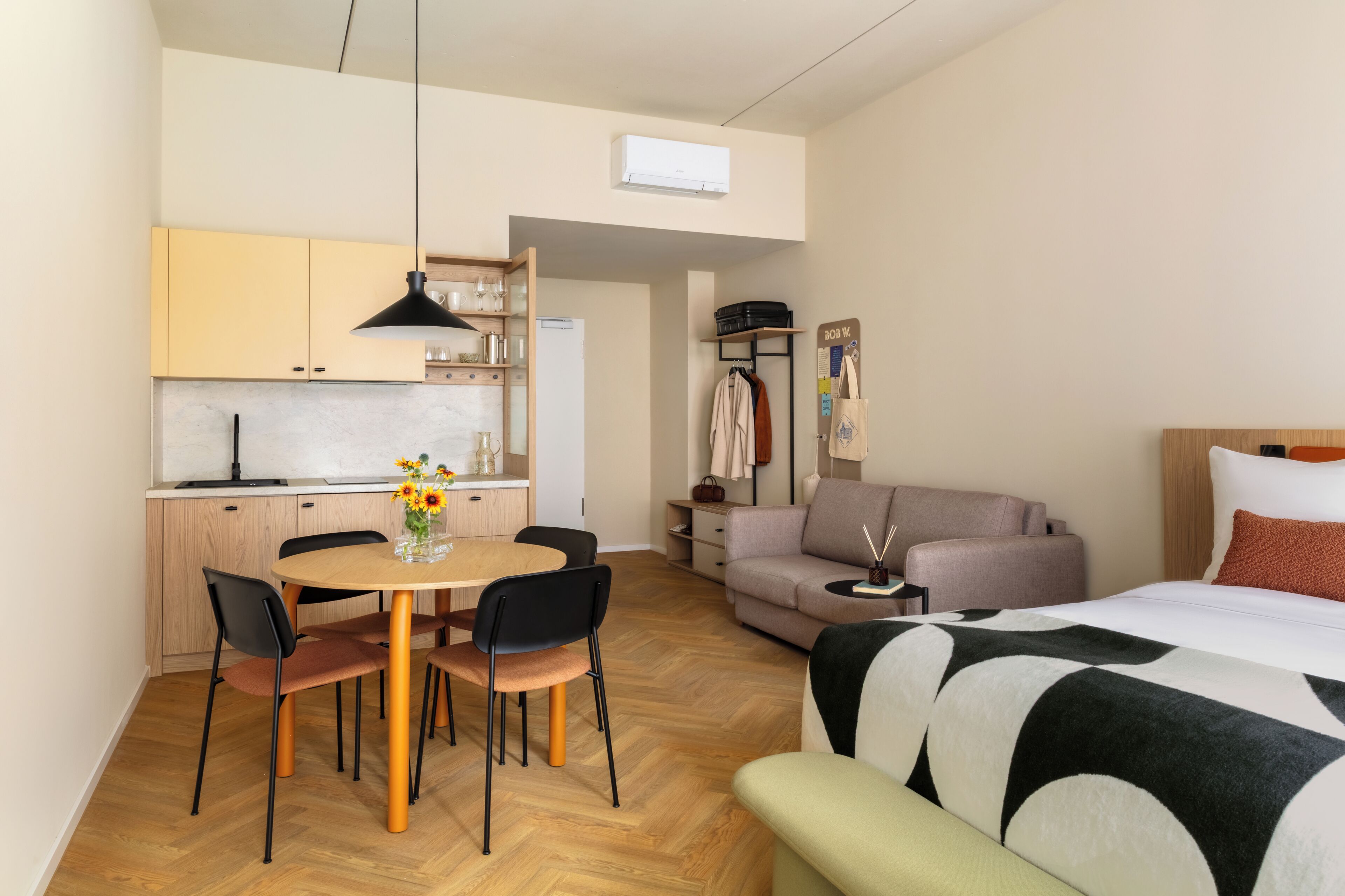 Un espacio habitable compacto con kitchenette, comedor, sofá y cama.