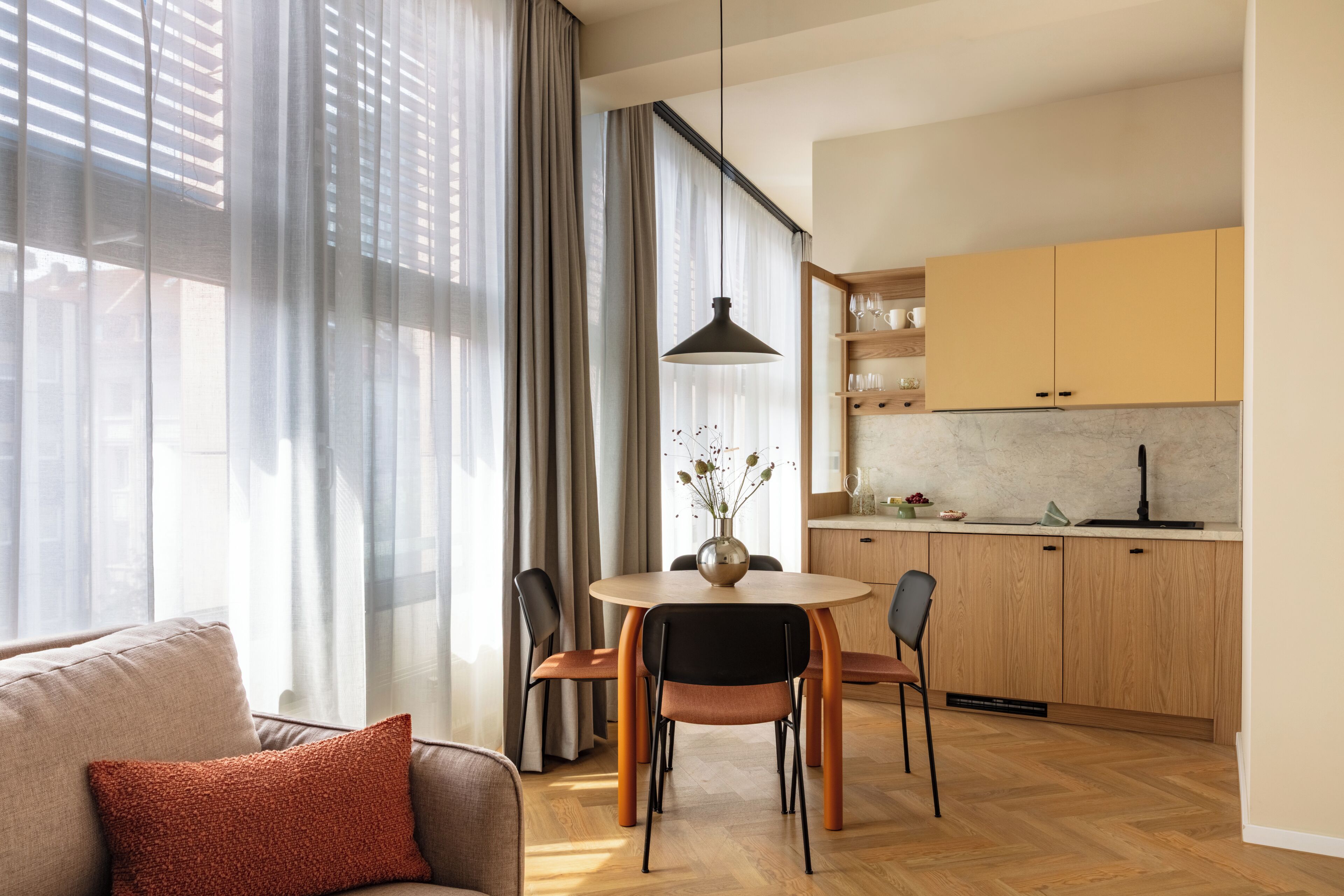 A modern kitchen with wooden cabinets and a dining area with a round table and chairs.