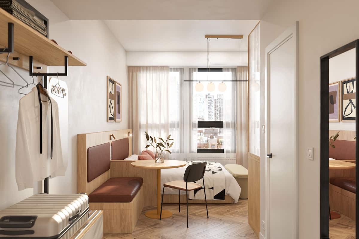 A modern hotel room with a bed, a seating area with a table and chairs, a window with curtains, and a view of the city.