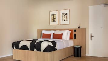 A modern bedroom with a wooden bed frame, white bedding, and two abstract paintings on the wall.