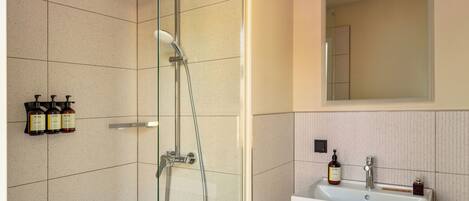 Un baño con ducha, lavabo y espejo.