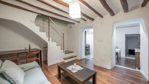Una sala de estar moderna con suelo de madera, un sofá, una mesa de centro y una escalera que conduce a otra habitación.