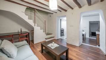 Una sala de estar moderna con suelo de madera, un sofá, una mesa de centro y una escalera que conduce a otra habitación.