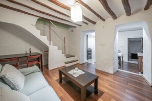 Ein modernes Wohnzimmer mit Holzboden, einer Couch, einem Couchtisch und einer Treppe, die in einen anderen Raum führt.