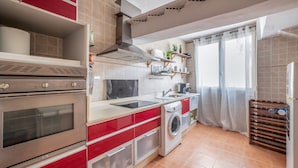 Una cocina con horno empotrado, lavadora y pileta.