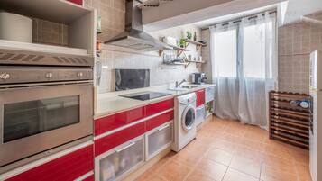 Una cucina con forno integrato, lavatrice e lavandino.