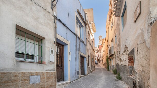 Una estrecha calle adoquinada bordeada por edificios históricos con puertas y ventanas visibles.