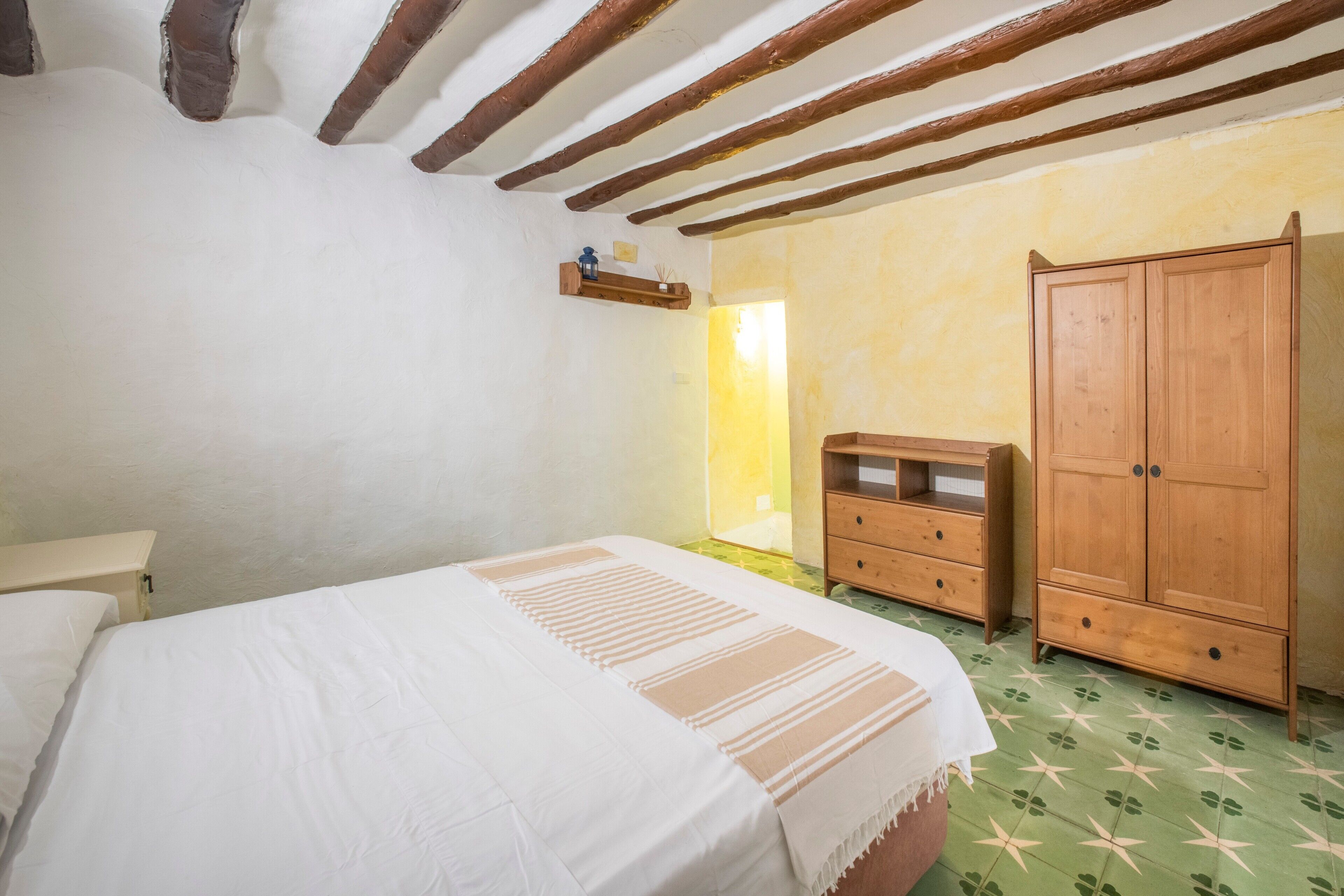 Un dormitorio con cama, armario de madera y cómoda pequeña.
