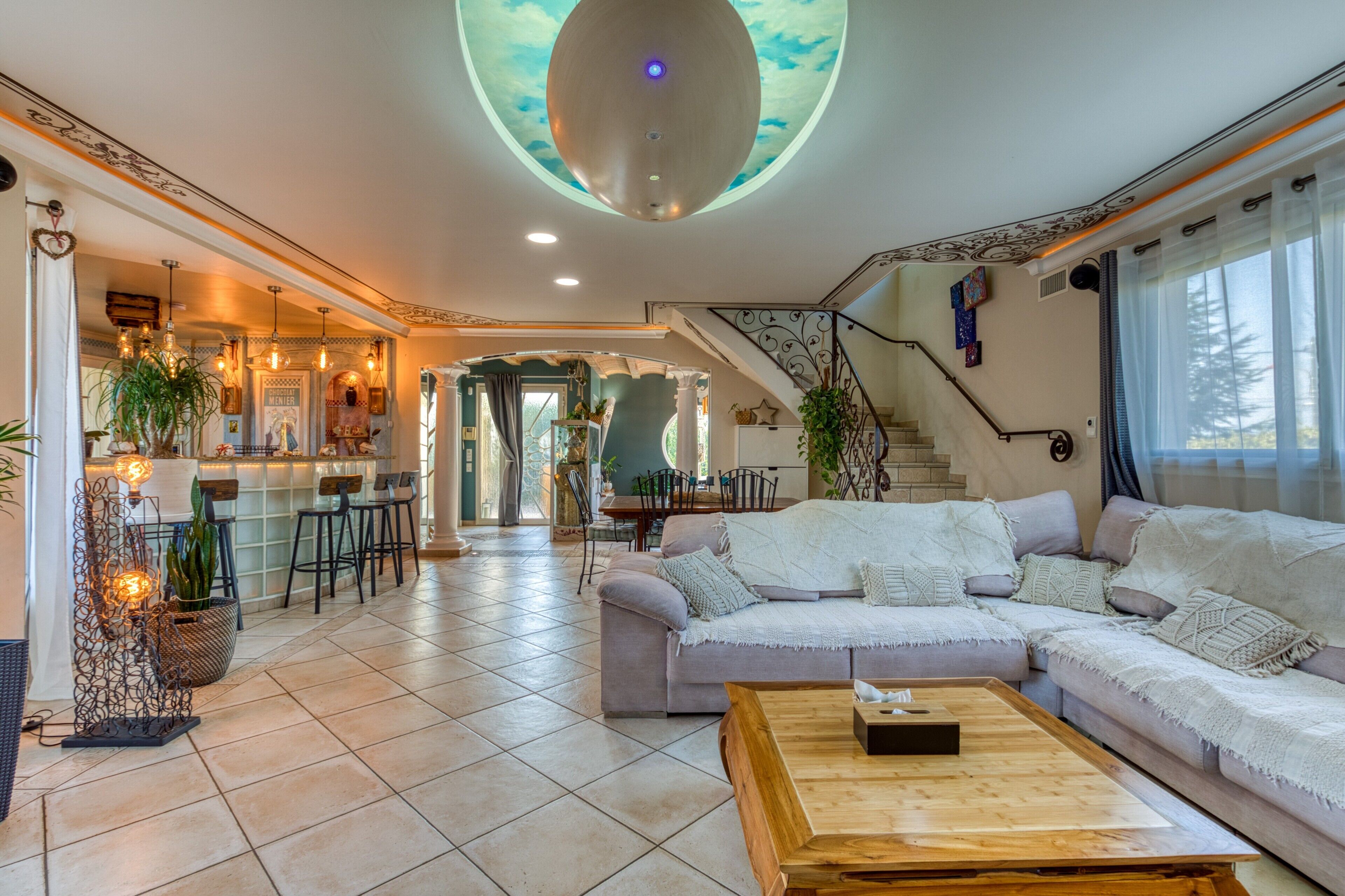 Un vaste espace de vie comprenant un grand canapé, une table basse et un escalier menant à un autre niveau.