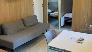 Una habitación moderna con sofá, una mesa de comedor, lámpara colgante y armario.