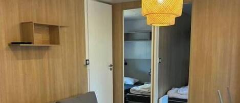 Ein modernes Zimmer mit einer Couch, einem Esstisch, einer Pendelleuchte und einem Kleiderschrank.