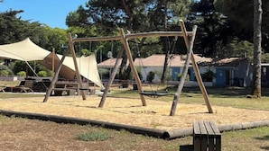 Un parque infantil con columpios y zona de picnic.
