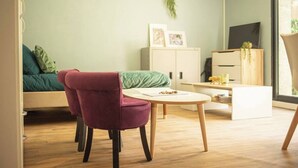Ett modernt vardagsrum med en soffa, en röd fåtölj, ett litet bord, ett skåp och en tv.