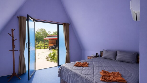 Un dormitorio con cama, ventana, puerta y vistas al exterior.