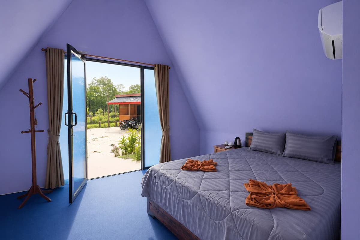 Un dormitorio con cama, ventana, puerta y vistas al exterior.