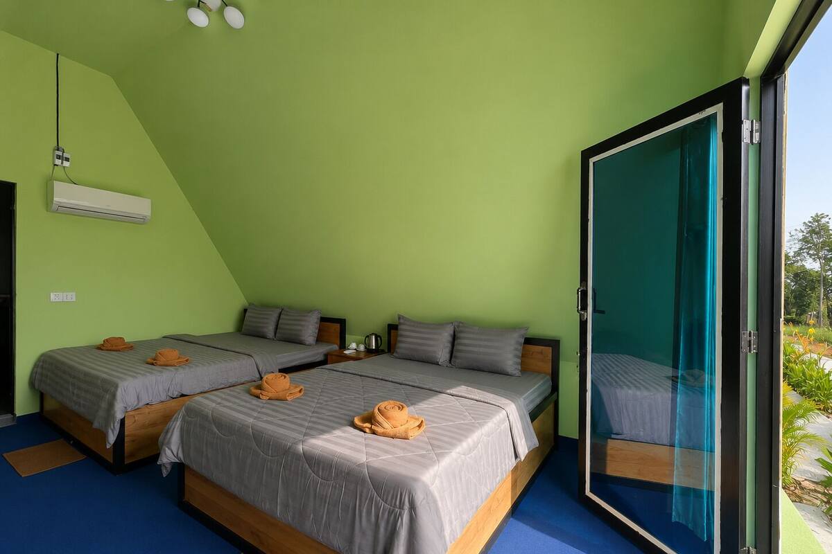 Una habitación con dos camas, una puerta corrediza de vidrio y vista a zonas verdes.