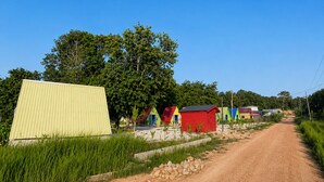 Una carretera rural con casas coloridas y un edificio amarillo grande.