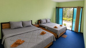 Una habitación de hotel con dos camas, vistas a la vegetación a través de una puerta corredera y una alfombra azul.