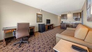 A hotel room with a kitchenette, a sofa, a desk, and a TV. - Newport Oceanfront Inn (Newport)
