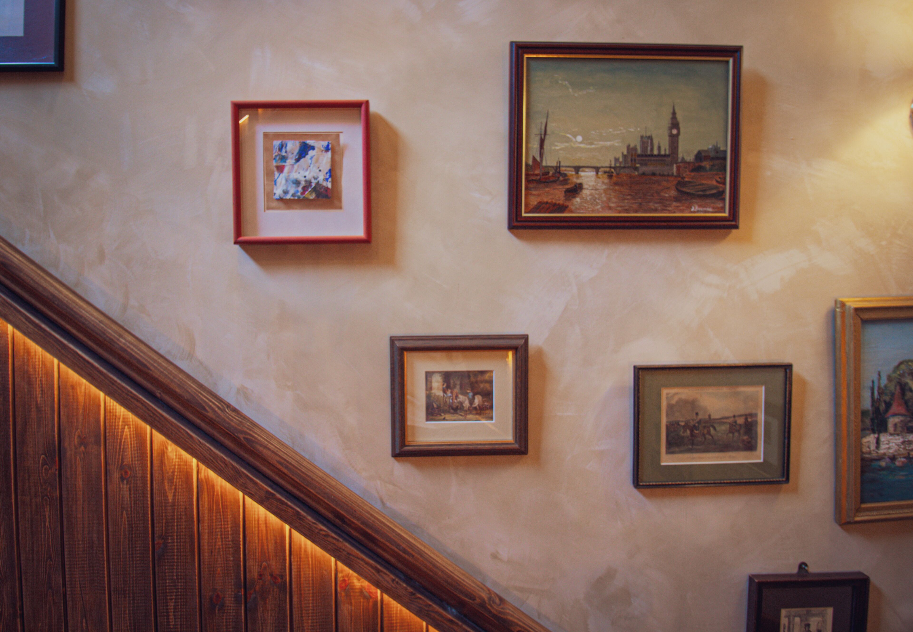 A staircase with wooden railings and a wall with framed pictures.