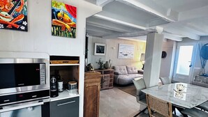Une cuisine moderne équipée d’appareils électroménagers en acier inoxydable, un coin repas avec une table en marbre et des œuvres d’art accrochées aux murs.