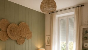 Une chambre à coucher avec un lit, des tables de chevet, une lampe, une fenêtre avec des rideaux et des éléments de décoration murale.