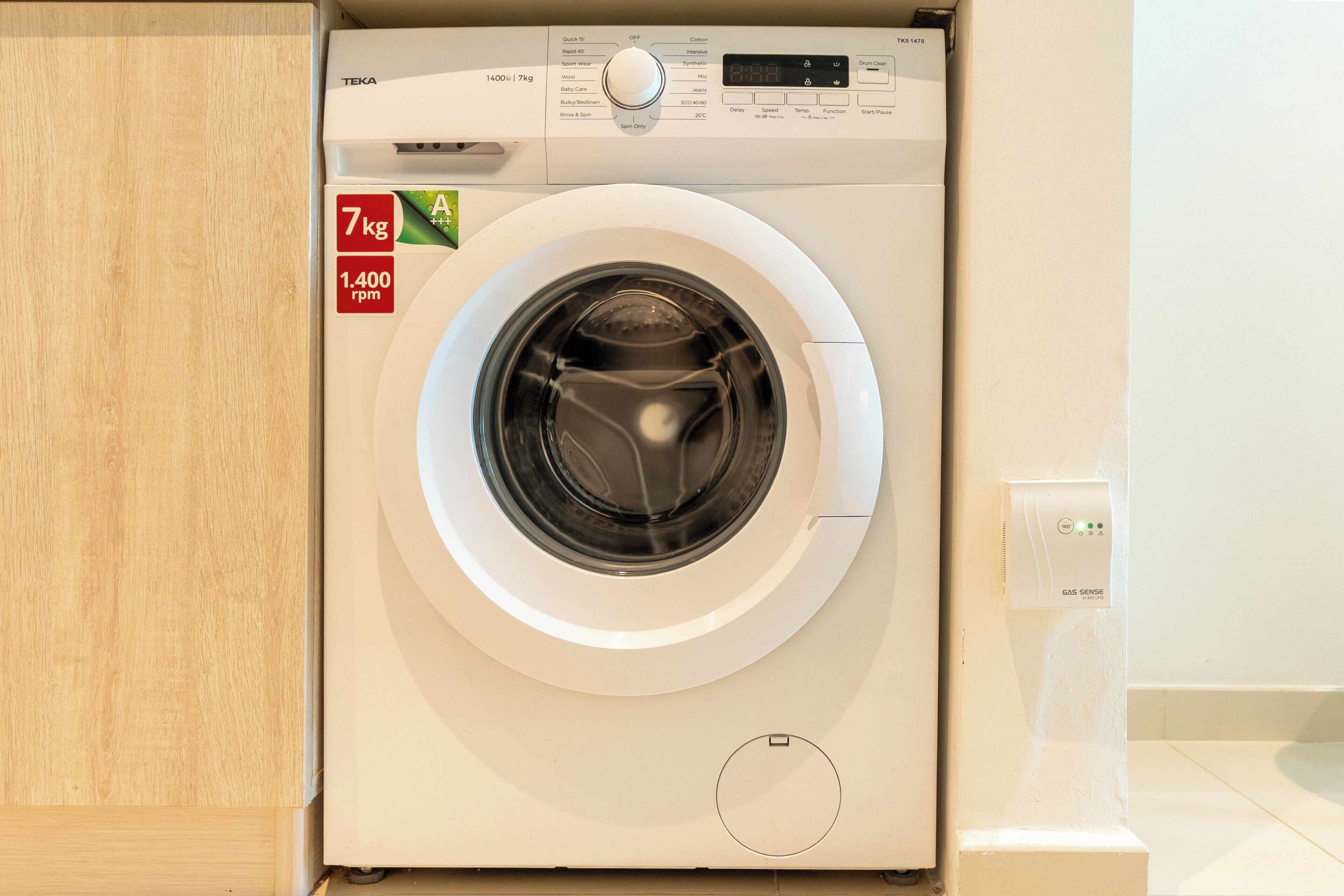 A front view of a white front-loading washing machine with a digital display, a control panel, and a 7 kg capacity label.