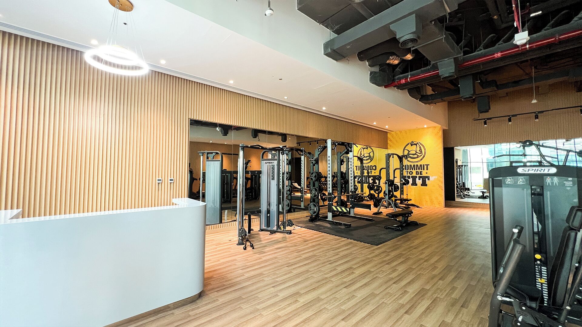 Une salle de sport équipée de divers appareils d’exercice, avec des murs en bois et un mur recouvert de miroirs.